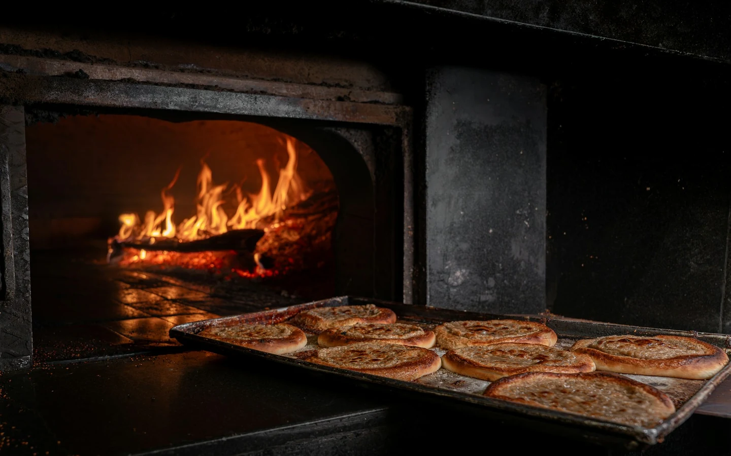 Flatbreads bake on the hearth of a wood-fired oven.