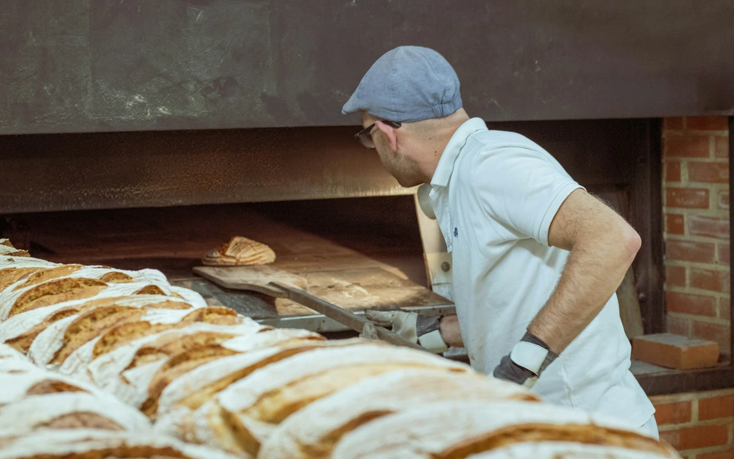 A baker works beside bread-production equipment in a bakery.