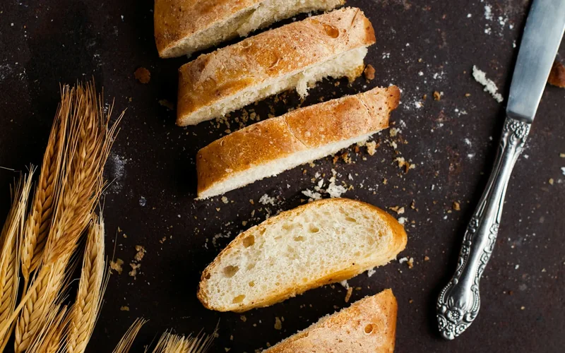 Sliced bread and a bread knife lie on a wooden board.