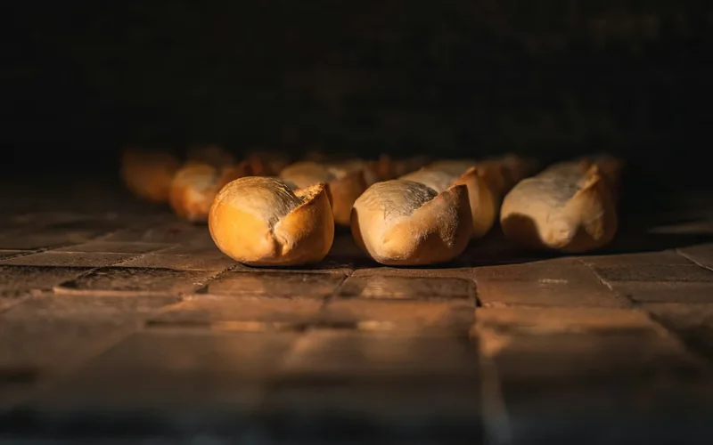 Rows of bread rolls bake inside a commercial oven.