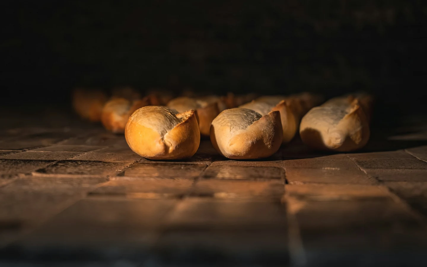 Rows of bread rolls bake inside a commercial oven.