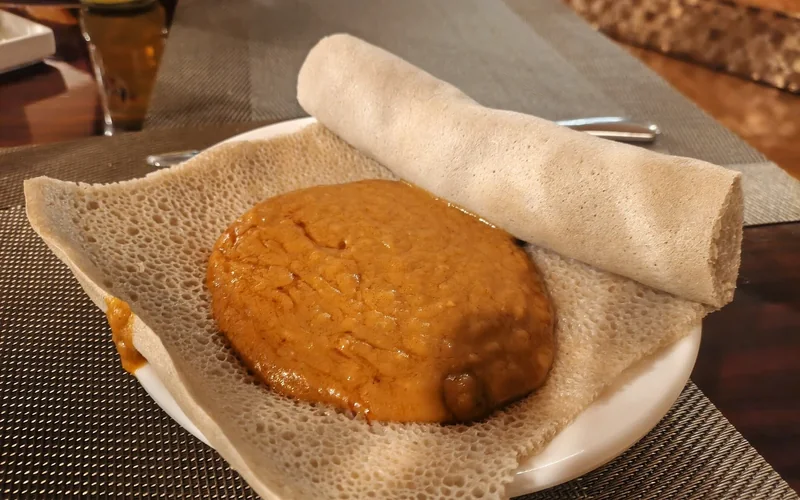 Injera flatbread with a porous surface is served on a plate.