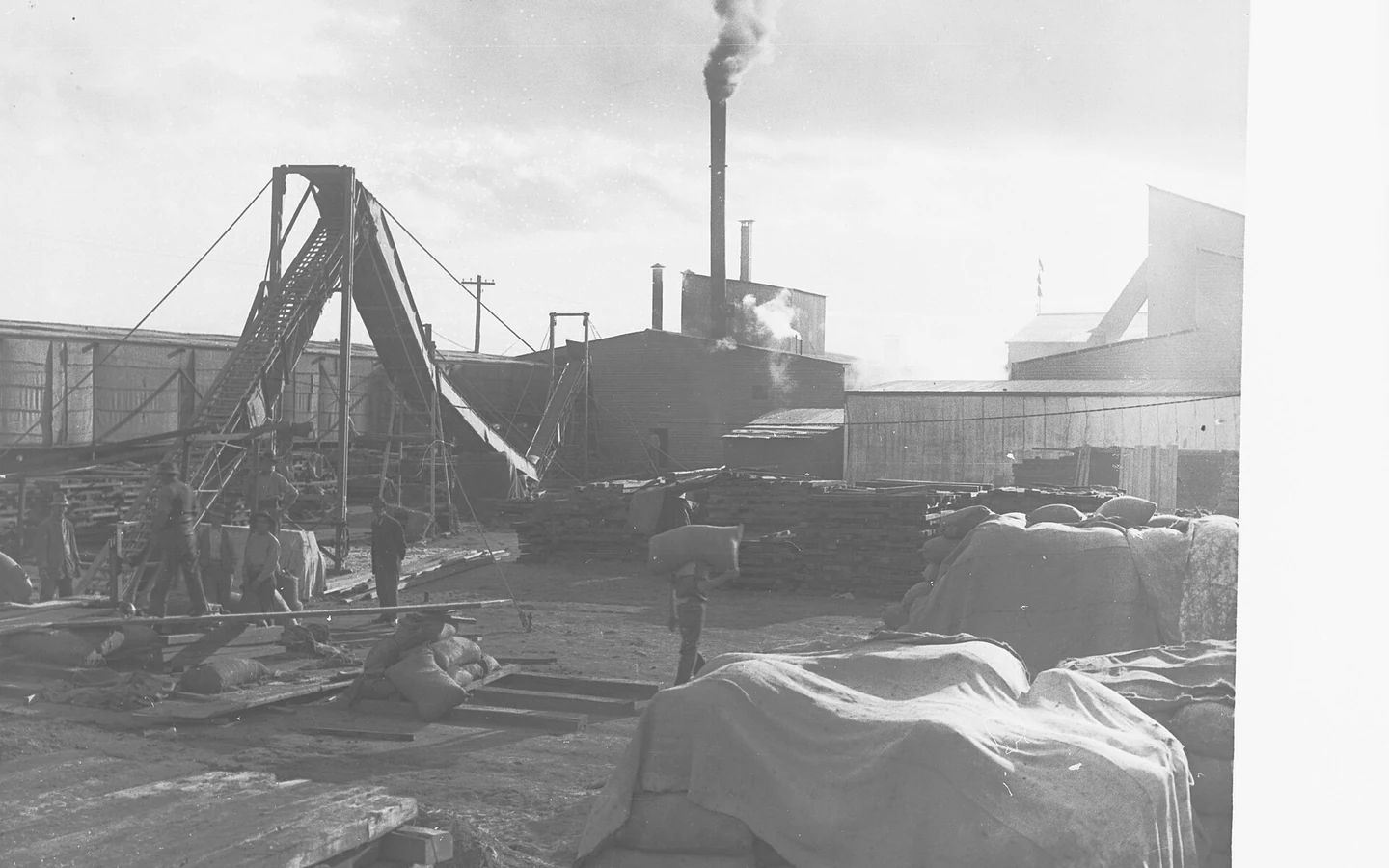 An archival photograph shows workers loading wheat sacks at a flour mill.