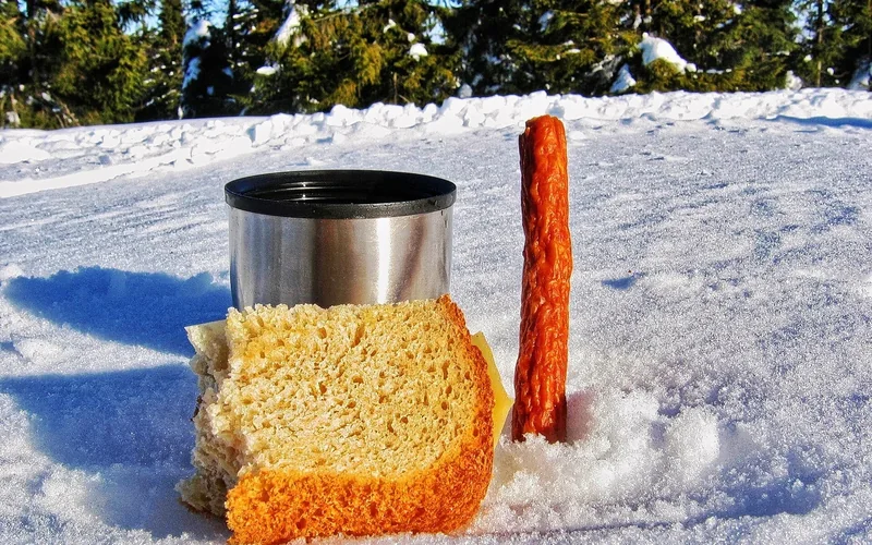 Bread and a simple meal are set out in a mountain landscape.