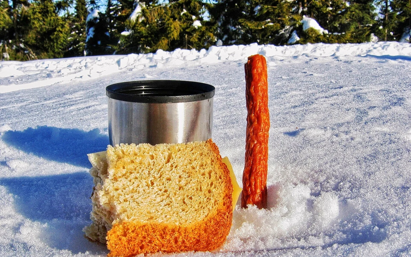 Bread and a simple meal are set out in a mountain landscape.