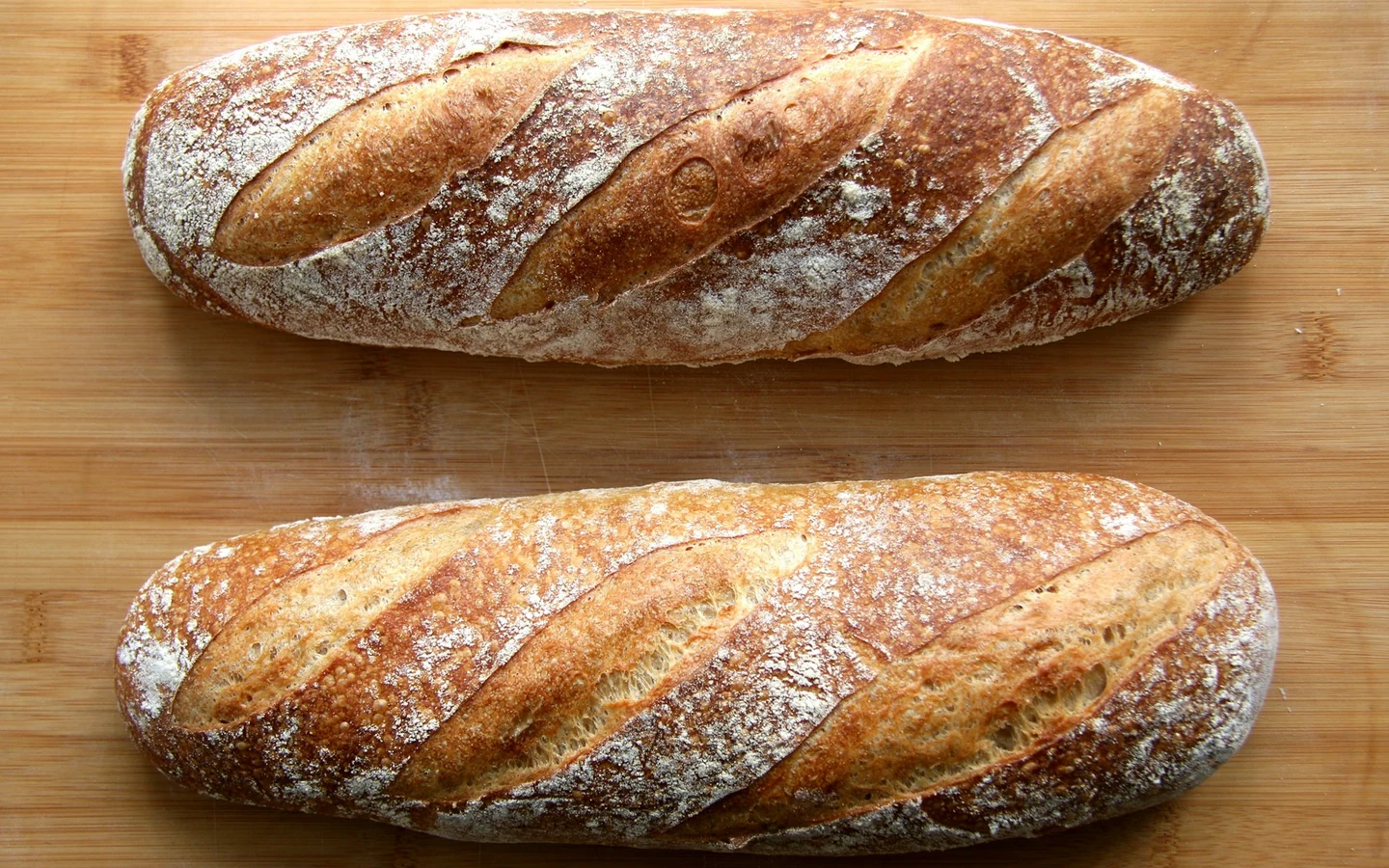A crusty loaf of bread rests on a wooden table.