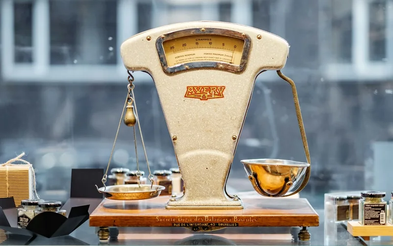 An old weighing scale with a metal pan and mechanical balance.