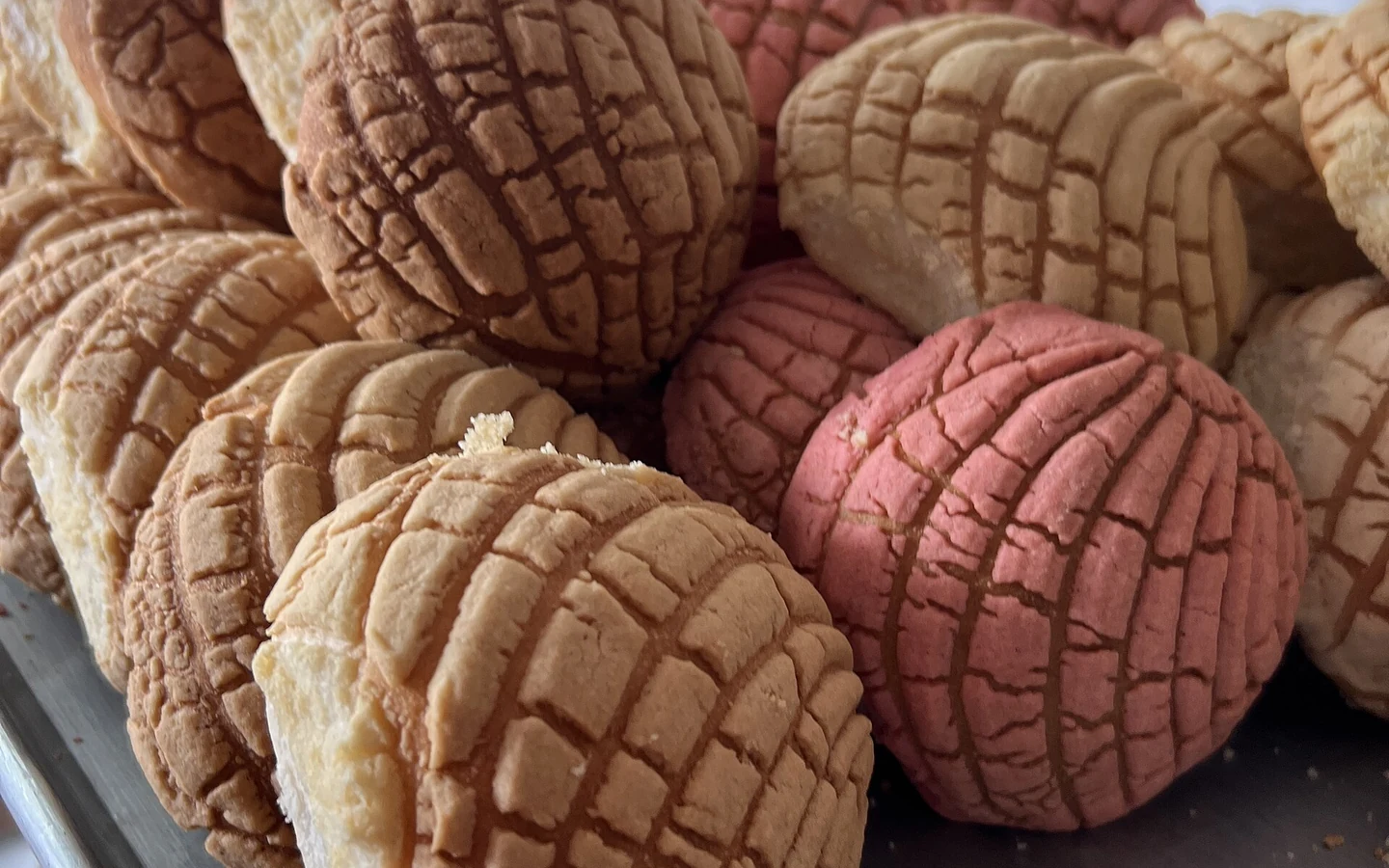 Concha sweet breads are arranged in a bakery display.