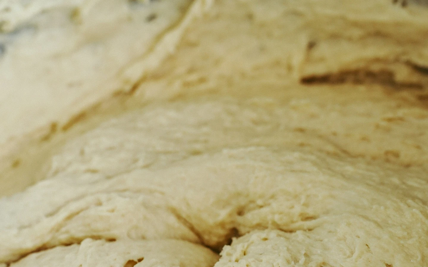 Wet bread dough is being mixed in a bowl.