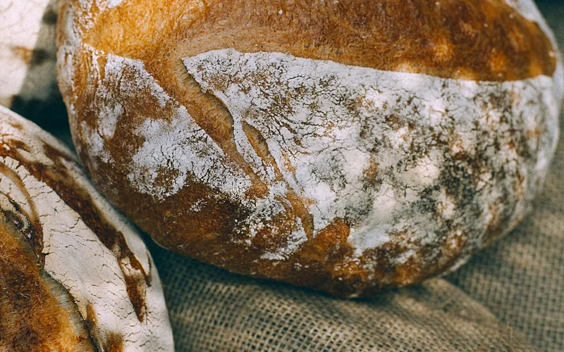 Rustic loaves of bread rest on coarse woven cloth.