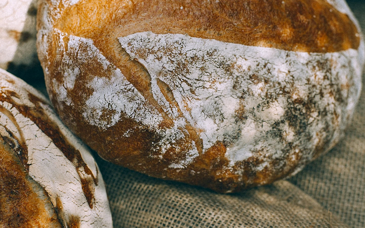 Rustic loaves of bread rest on coarse woven cloth.